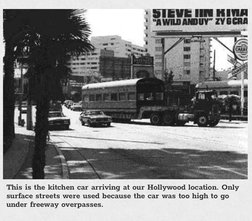 Black and white photo of a large kitchen car being towed down a city street.