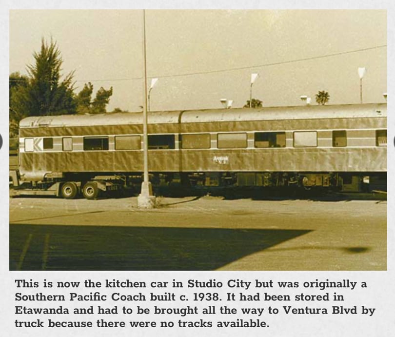 A vintage sepia-toned photo of a train car being transported on a flatbed truck.