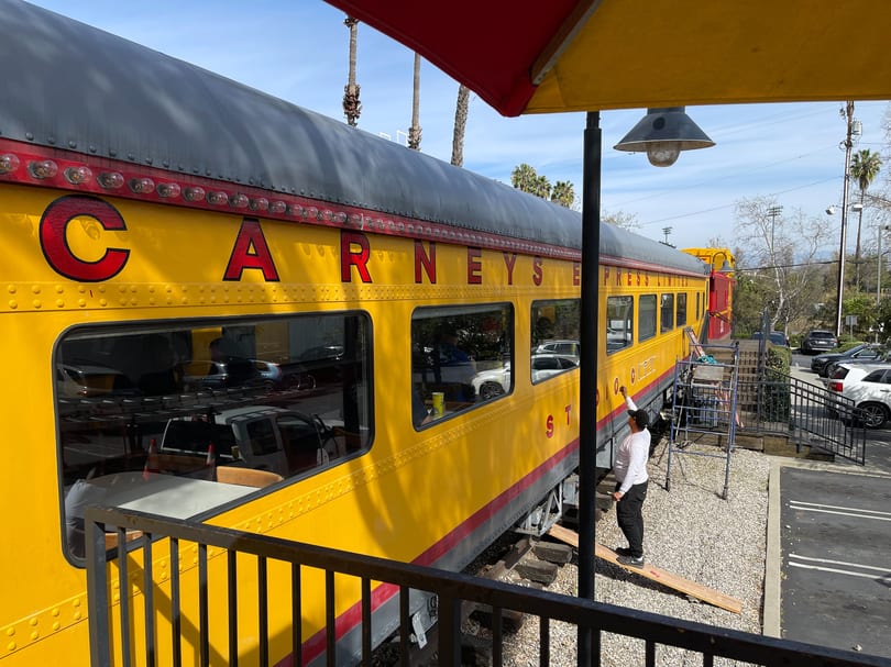 A bright yellow train car with "CARNEY'S EXPRESS" painted on its side, serving as a restaurant.