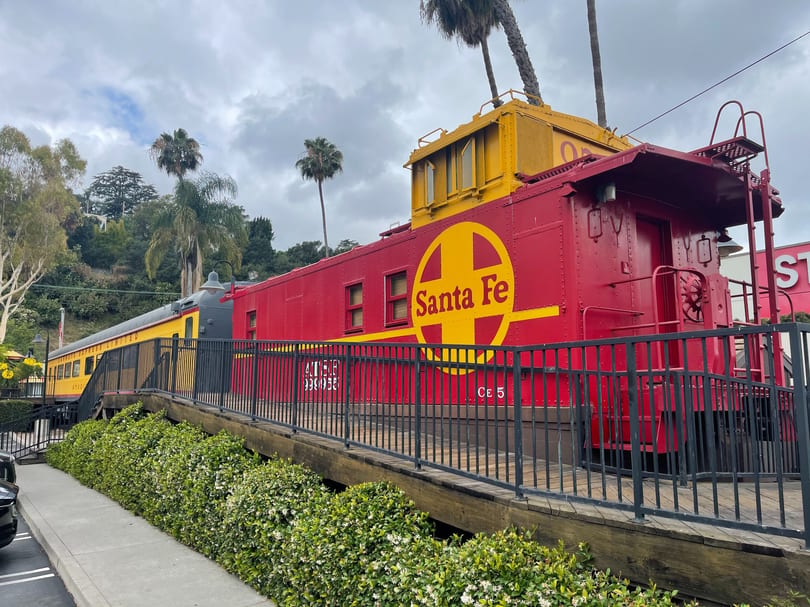 Red and yellow Santa Fe train cars, converted into a restaurant, sit on a raised platform.